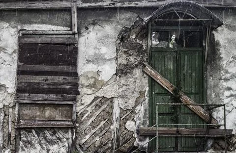 Destroyed old building with a boarded up window and a door in the rain Fotos de archivo