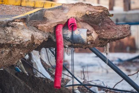 Destroyed road after storm with broken pipes out Stock Photos