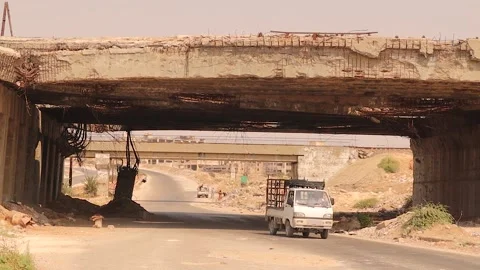 Destroyed war bridge in Aleppo Syria with car passing as symbol of resilience Stock Footage 317363773