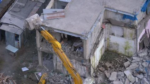 Destroying Old Concrete House Using Mechanical Arm of Bulldozer on Construction Foto stock