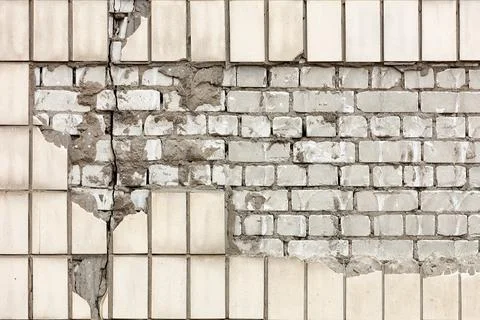 Destruction of the wall facade with falling off lined rectangular facade tile Stock Photos