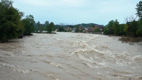 A destructive river with raging dirty brown water rushes down Stock Footage 247395446