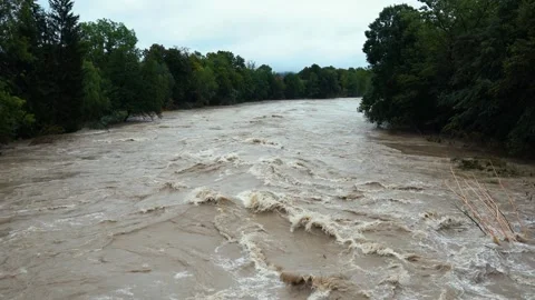 A destructive river with raging dirty brown water rushes down Stock Footage 247395595