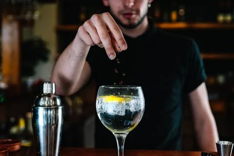 Detail of a bartender's hands adding ingredients into a crystal glass with ice Stock Photos