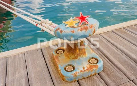 Detail of a bitt with two starfishes and a rope for mooring at the harbor Stock Photos