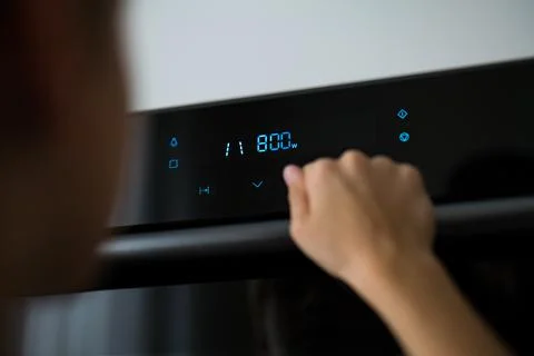 Detail of a child's hand while using a microwave. touch display microwave oven Foto stock