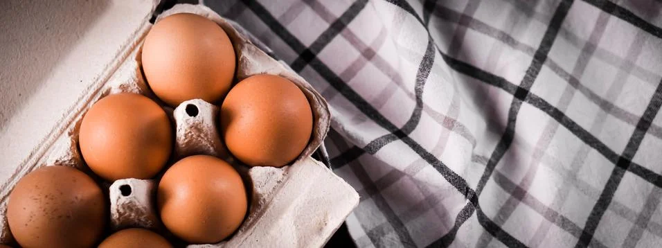 Detail close-up of chicken eggs in egg box on the old brown wooden background. Foto stock