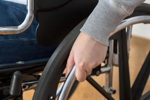Detail of disabled woman holding a hand on wheel of a wheelchair. Stock Photos