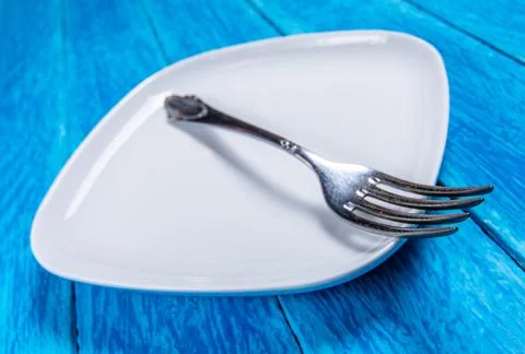 Detail of empty squared white ceramic plate and silver cutlery on blue wooden 스톡 사진