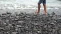 Detail of guy legs walking in the gravel on the beach HD Footage