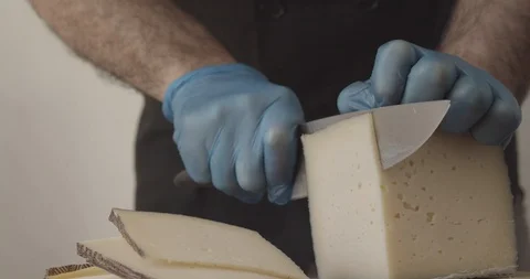 Detail of the hands of a chef with protective gloves cutting cheese Stock Footage 129671882