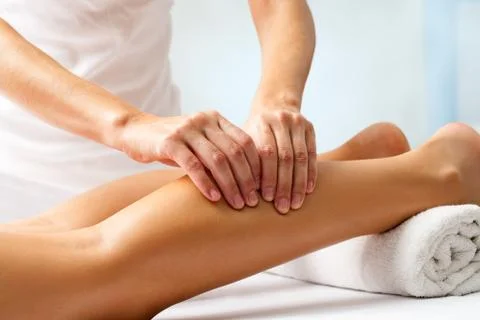 Detail of hands massaging human calf muscle. Stock Photos