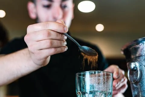 Detail of the hands of a young waiter, adding brown sugar in a large crystal Stock Photos