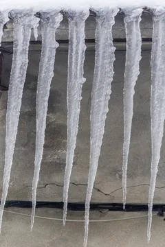 Detail of ice carambanos on the facade of a house, vertical photo Stock Photos