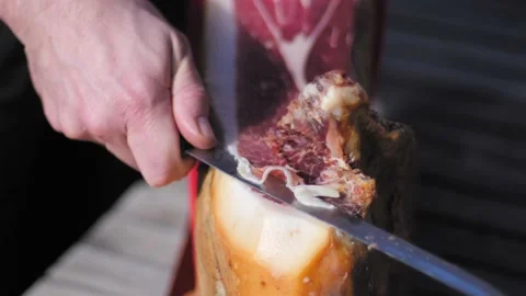 Detail of man cutting a slice of dried spanish jamon serrano on wood table. 스톡 동영상 152244784