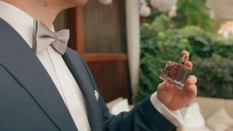 Detail of a man spraying perfume while wearing a suit, with plants in the Stock Footage 101754371