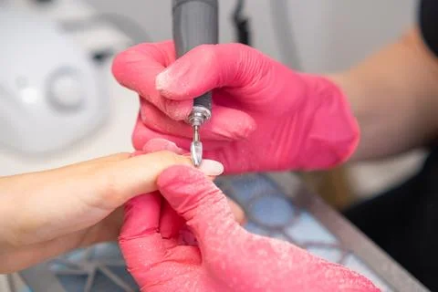 Detail oriented manicure using a nail drill machine at a salon in a well lit Stock Photos