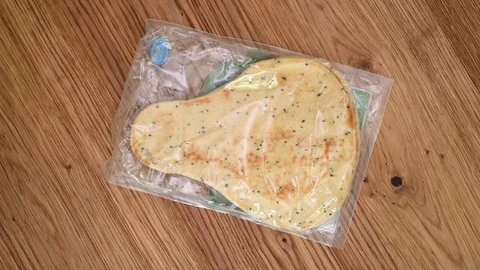 Detail of plastic packed naan bread on a wooden table Stock Footage 113222442