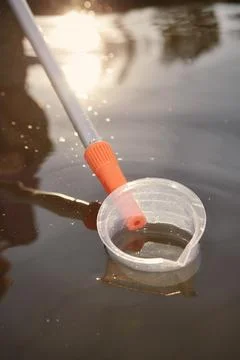 Detail of plastic sampling beaker on rod with sample of water Stock Photos