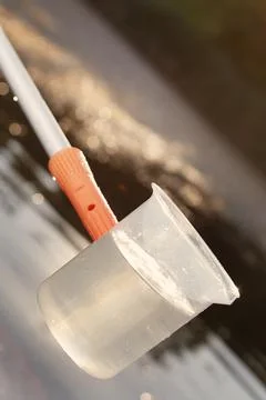 Detail of plastic sampling beaker on rod with sample of water Foto stock