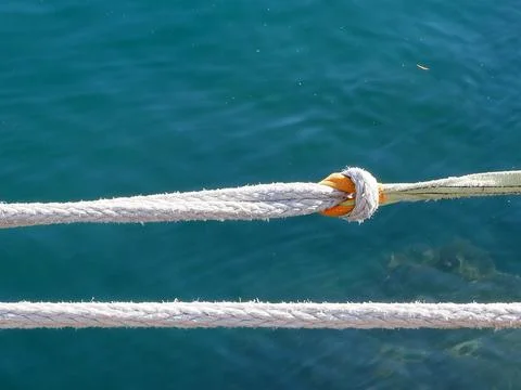 Detail of ropes with knot securing a boat at a marina with turquoise waters Stock-Fotos