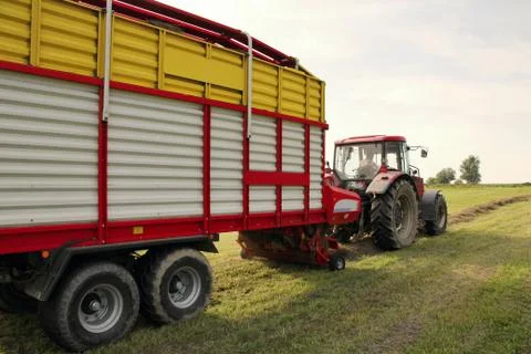 Detail of self loading silage wagon, picking up hay from small meadow, stra.. Stock Photos