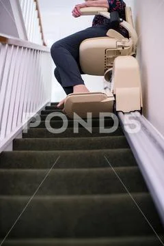 Detail Of Senior Woman Sitting On Stair Lift At Home To Help Mobility Stock Photos