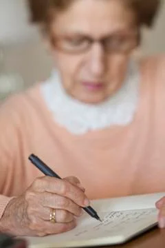 Detail of a senior woman writing in a note book Stock Photos
