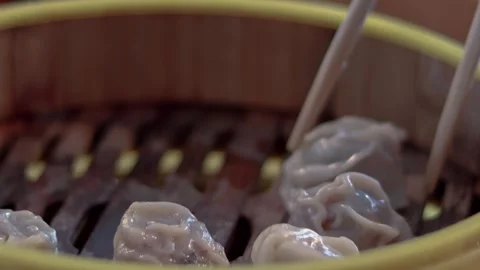 Detail shot, picking up a steaming har gow or shrimp dumplings from a bamboo Stock Footage 346247784