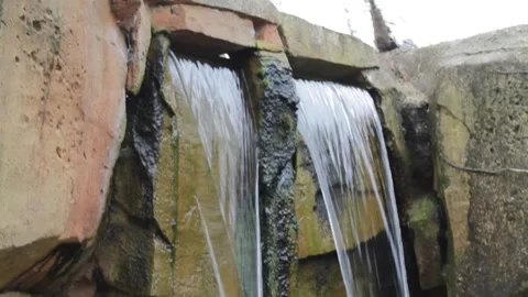 Detail of a small waterfall flowing down a stone wall in a park Stock Footage 250147405