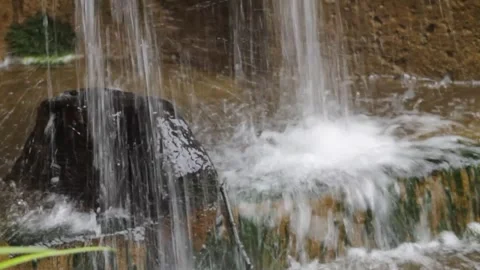 Detail of a small waterfall flowing down a stone wall in a park Stock Footage 250147409