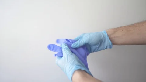 Detail of some hands putting on blue medical gloves on a white background Stock Footage 127217066