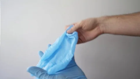 Detail of some hands putting on blue medical gloves on a white background Stock Footage 127217525