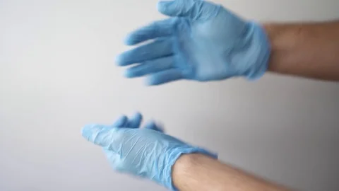 Detail of some hands putting on blue medical gloves on a white background Stock Footage 127217588