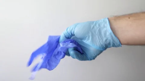 Detail of some hands putting on blue medical gloves on a white background Stock Footage 127217963
