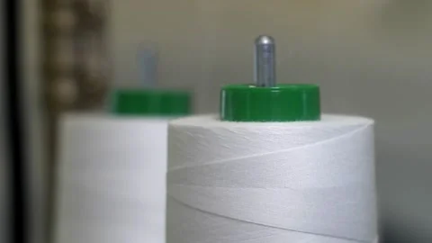 Detail with thread unwinding from bobbins of thread from a sewing machine fr Stock Footage 145655944