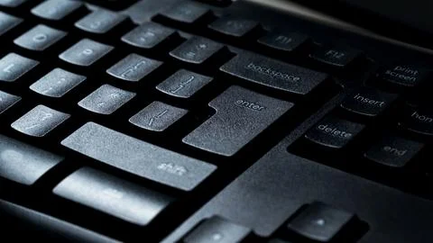 Detail view of desktop computer keyboard with light shining on keys. Stock Photos