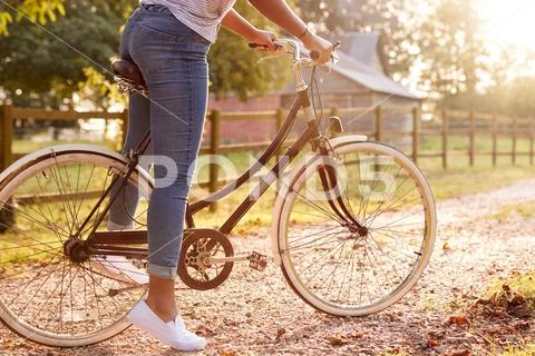 Detail Of Woman Riding Bike Along Country Lane At Sunset Stock Photos