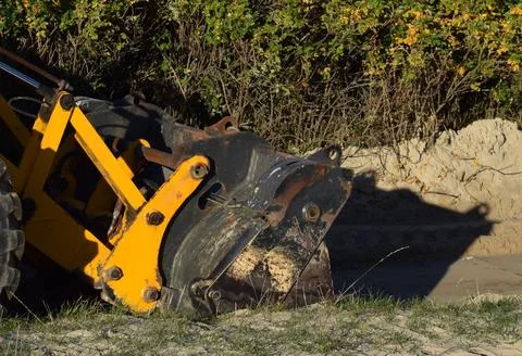 Detail of Yellow Backhoe Loader Working on Sand in a Public Park Stock Photos