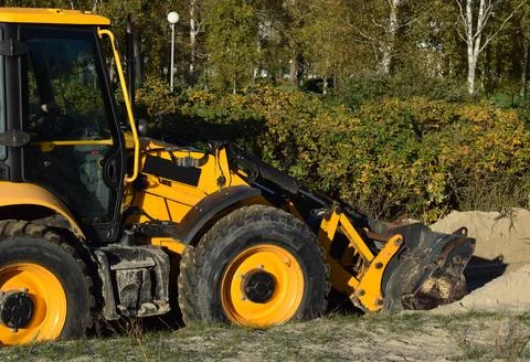 Detail of Yellow Backhoe Loader Working on Sand in a Public Park Stock Photos