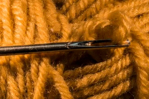 Detail of yellow wool thread threaded on a needle Stock Photos