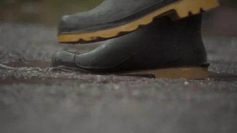 A detailed and vivid capture of a boot splashing through large puddles Stock Footage 310169622