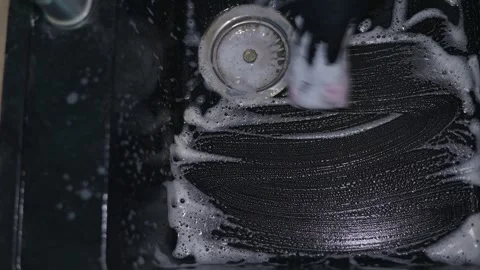 Detailed cleaning process of a dark surface is displayed. Soap and water create 스톡 동영상 337642845