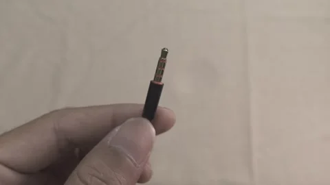 A Detailed Close-Up of a 3.5mm Audio Jack Plug Held by Hand Stock Footage 307069610