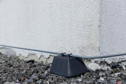 Detailed Close-Up of a Cable Holder Secured to a Wall, Embedded in Gravel Stock Photos