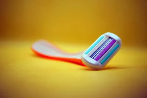 A detailed close up image of a razor placed on a bright yellow surface Stock Photos