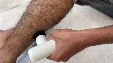 Detailed close up of a person using a white percussion massage gun Видео 328352279