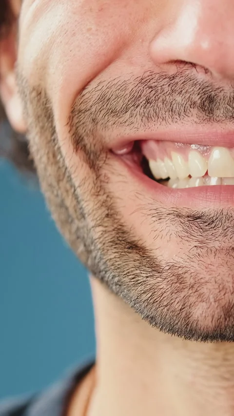 Detailed close-up shot of half face man's smile in studio on blue background Stock Footage 255962600