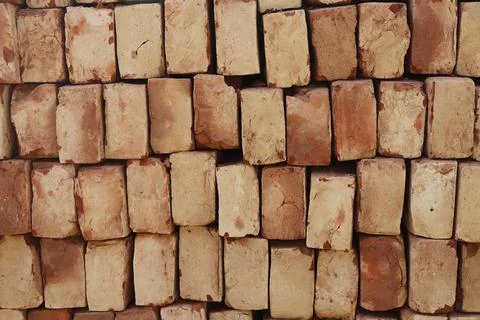 Detailed close up showcases a stack of pale red and tan bricks, arranged in a Stock Photos