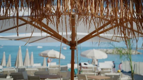 Detailed close up of straw canopy textures hanging above blurred beach umbrellas Stock Footage 337010439